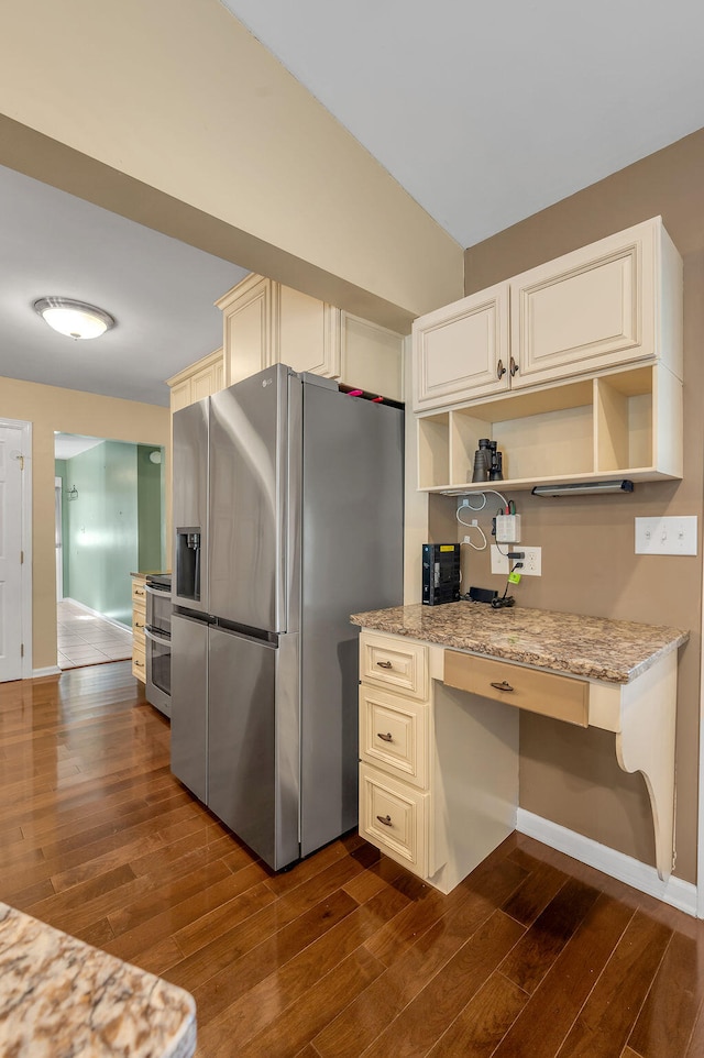 kitchen with cream cabinetry, built in desk, stainless steel fridge with ice dispenser, light stone countertops, and dark hardwood / wood-style flooring