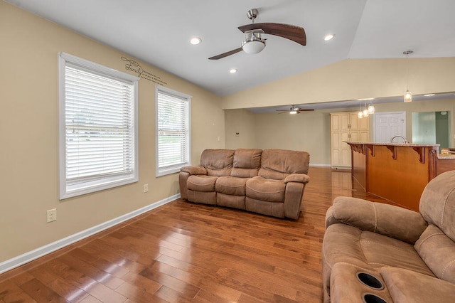 living room featuring light hardwood / wood-style flooring, lofted ceiling, ceiling fan, and a healthy amount of sunlight