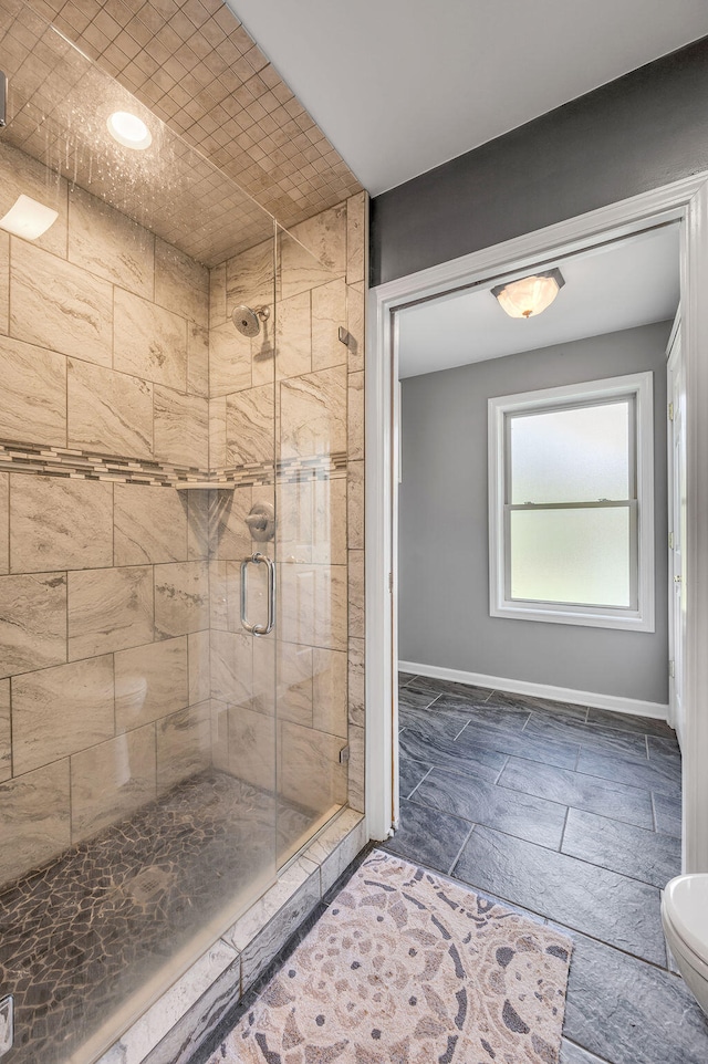 bathroom featuring a shower with shower door and toilet