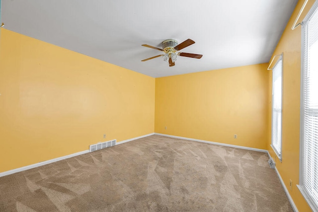 spare room featuring a healthy amount of sunlight, carpet, and ceiling fan