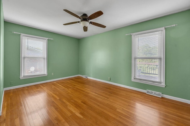 spare room with ceiling fan, wood-type flooring, and a wealth of natural light