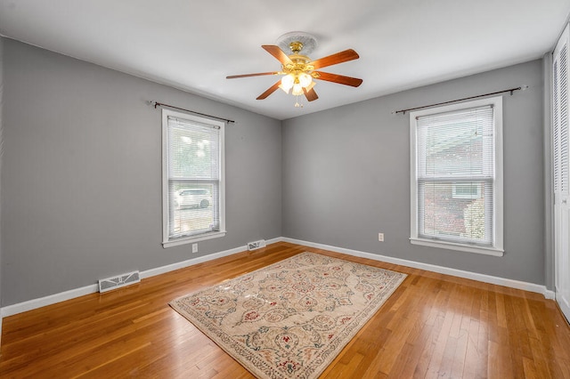 unfurnished room with a healthy amount of sunlight, hardwood / wood-style floors, and ceiling fan