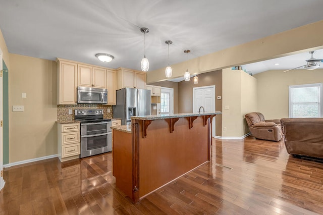 kitchen with wood-type flooring, a breakfast bar area, appliances with stainless steel finishes, and a wealth of natural light