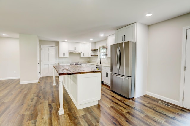 kitchen featuring appliances with stainless steel finishes, white cabinetry, dark wood-type flooring, a kitchen island, and wood counters