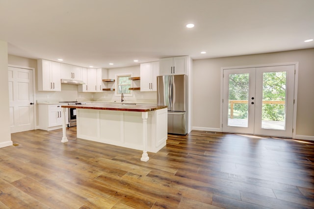 kitchen with appliances with stainless steel finishes, wood-type flooring, white cabinetry, and a center island