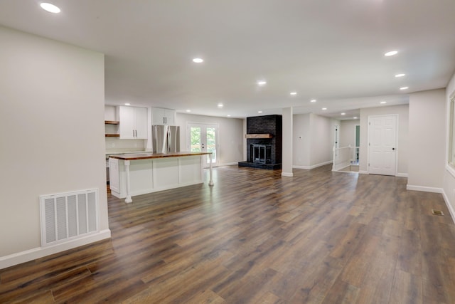 unfurnished living room with a brick fireplace and dark hardwood / wood-style flooring