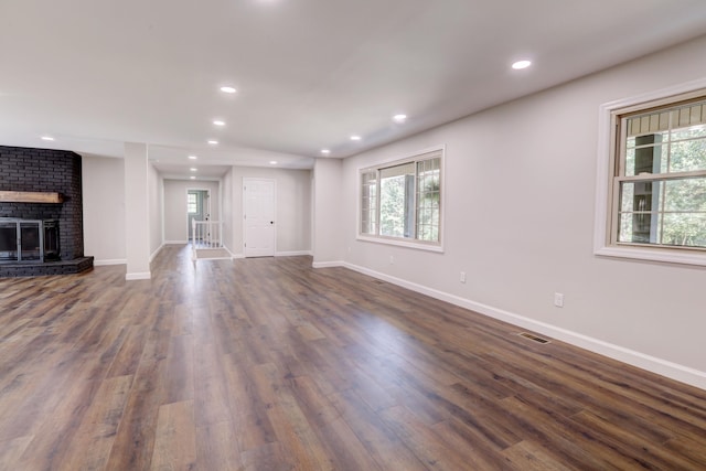 unfurnished living room featuring a brick fireplace and dark hardwood / wood-style floors