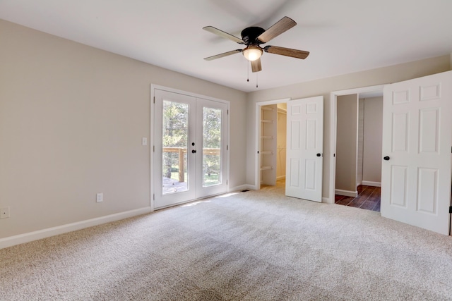 unfurnished bedroom featuring dark carpet, ceiling fan, a walk in closet, and french doors