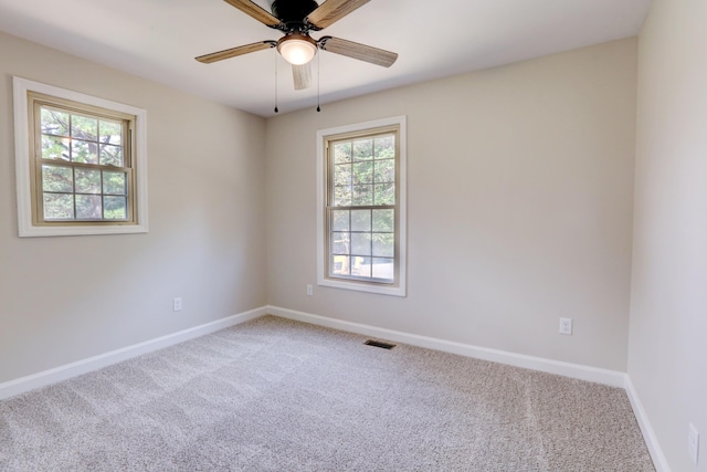 carpeted empty room featuring a wealth of natural light and ceiling fan