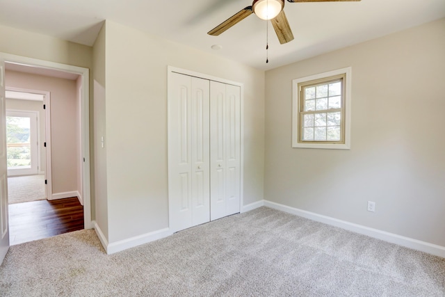 unfurnished bedroom with a closet, multiple windows, light colored carpet, and ceiling fan