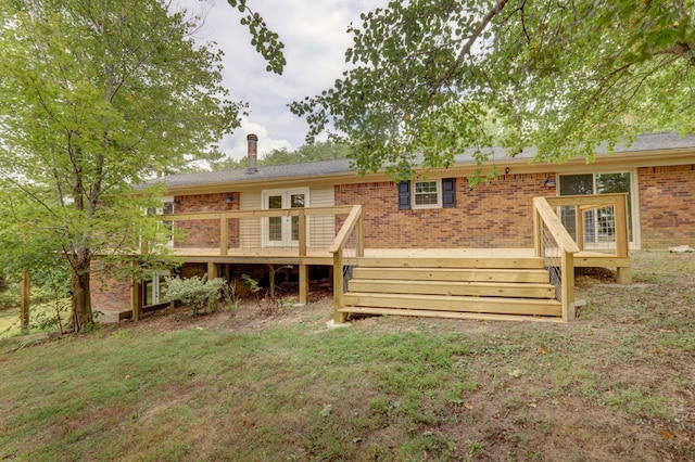 rear view of house featuring a wooden deck and a lawn