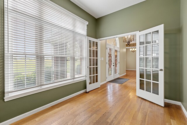 interior space featuring light wood-type flooring, an inviting chandelier, and french doors