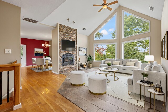 living room featuring ceiling fan with notable chandelier, hardwood / wood-style flooring, a fireplace, and high vaulted ceiling