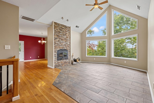 unfurnished living room featuring ceiling fan with notable chandelier, a fireplace, light wood-type flooring, and high vaulted ceiling