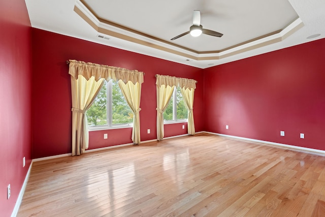 spare room featuring light wood-type flooring, a raised ceiling, crown molding, and ceiling fan