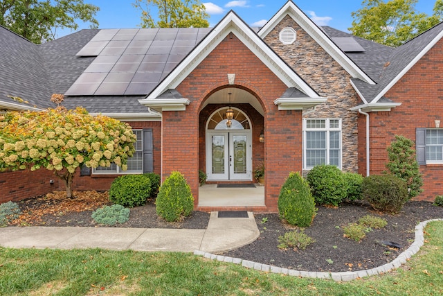 706 Hunter Dr, Lancaster, KY 40444 - property entrance with french doors, brick siding, roof mounted solar panels, and a shingled roof