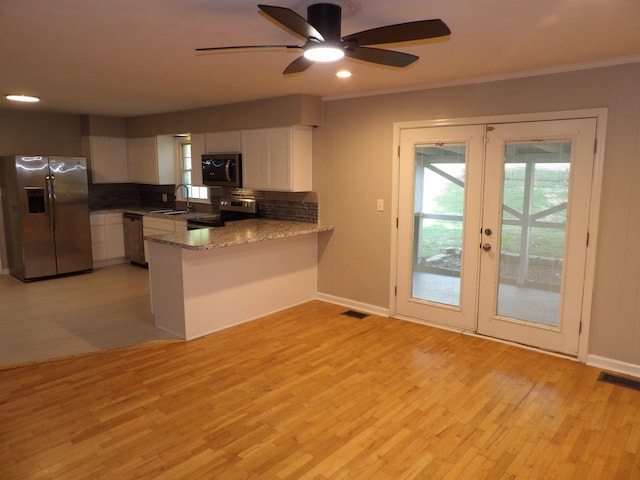 kitchen with white cabinets, kitchen peninsula, light hardwood / wood-style flooring, stainless steel appliances, and ceiling fan