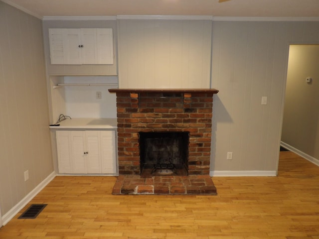 unfurnished living room with light hardwood / wood-style flooring, a brick fireplace, and ornamental molding