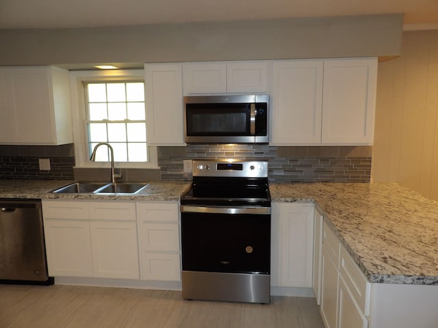 kitchen with appliances with stainless steel finishes, decorative backsplash, white cabinetry, and sink