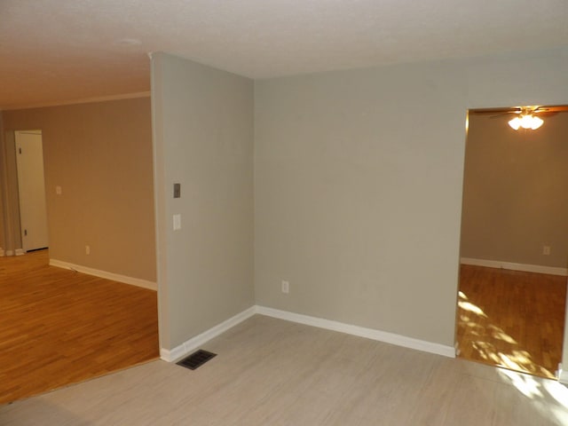 empty room featuring light wood-type flooring, crown molding, and ceiling fan