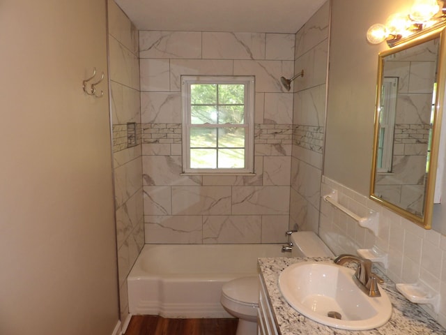 full bathroom with tile walls, hardwood / wood-style flooring, vanity, tiled shower / bath, and toilet