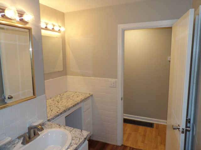 bathroom with tile walls, wood-type flooring, and vanity