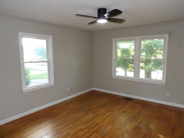 empty room featuring ceiling fan, plenty of natural light, and hardwood / wood-style floors