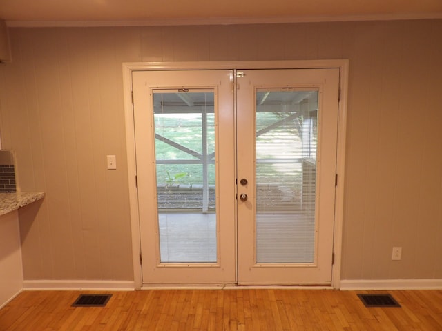 doorway featuring french doors, light hardwood / wood-style flooring, and wood walls