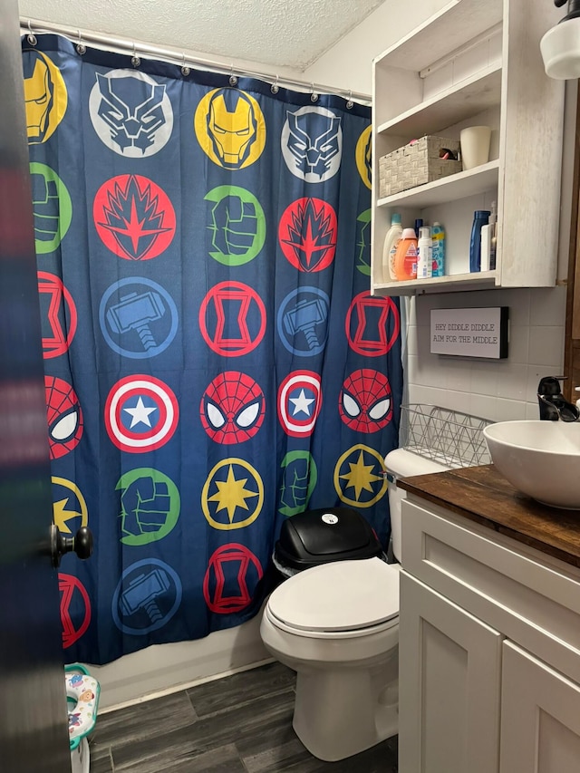 bathroom featuring wood-type flooring, a textured ceiling, backsplash, vanity, and toilet