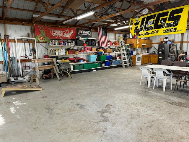 garage with black refrigerator with ice dispenser and a workshop area