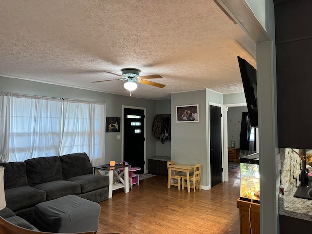 living room with a textured ceiling, wood-type flooring, and ceiling fan