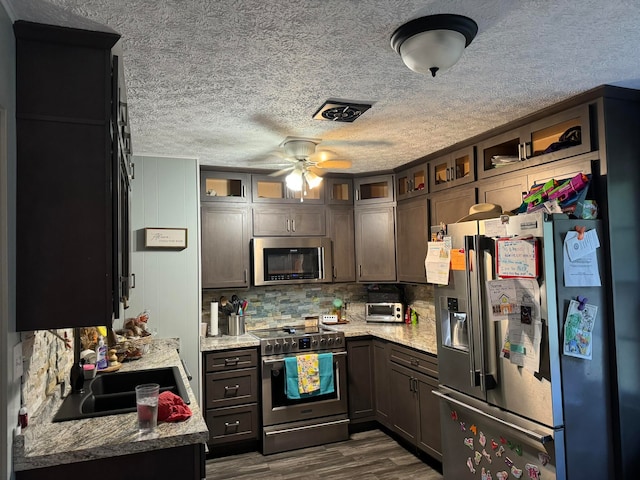 kitchen with dark hardwood / wood-style flooring, ceiling fan, stainless steel appliances, and light stone counters