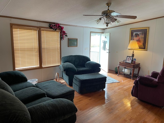 living room with ceiling fan, ornamental molding, a textured ceiling, and light hardwood / wood-style flooring