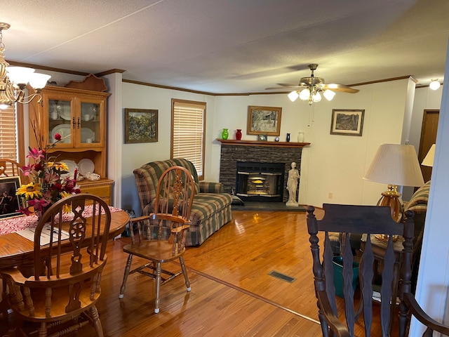 living room featuring a fireplace, wood-type flooring, a textured ceiling, and ornamental molding