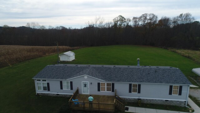 view of front of property featuring a front lawn, a storage unit, and a deck