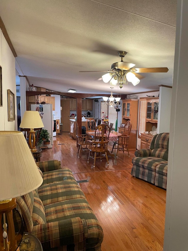 living room featuring hardwood / wood-style flooring, ceiling fan, crown molding, and a textured ceiling