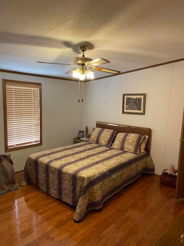 bedroom with ceiling fan, hardwood / wood-style floors, and a textured ceiling