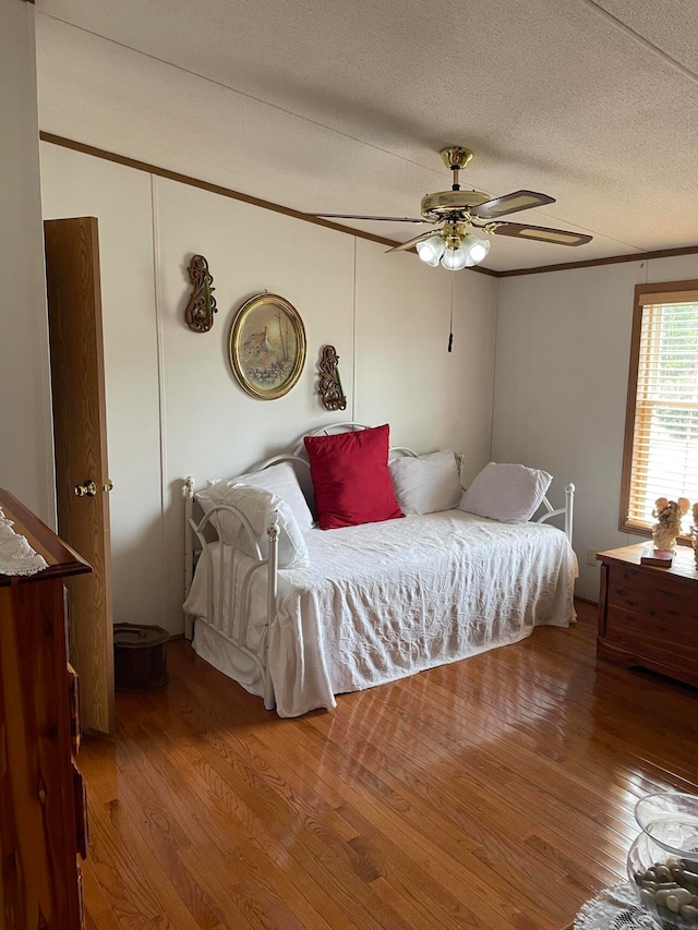 bedroom featuring ceiling fan, hardwood / wood-style floors, and a textured ceiling