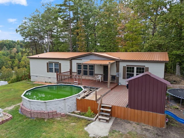 back of house with a trampoline, a yard, and a swimming pool side deck