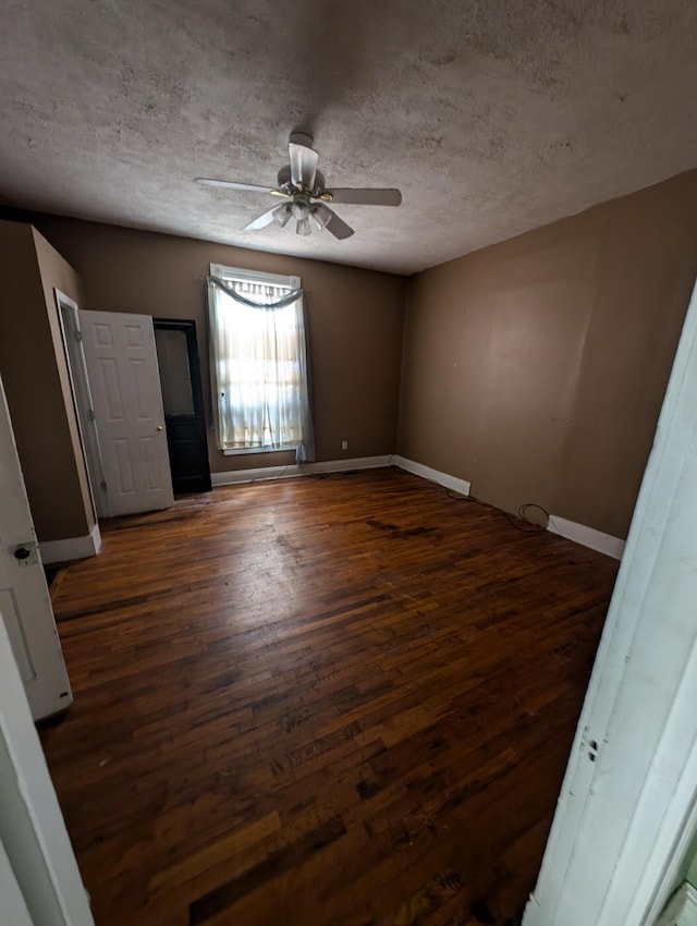 unfurnished room featuring a textured ceiling, dark wood-type flooring, and ceiling fan