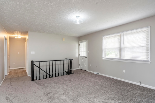 carpeted empty room with a textured ceiling