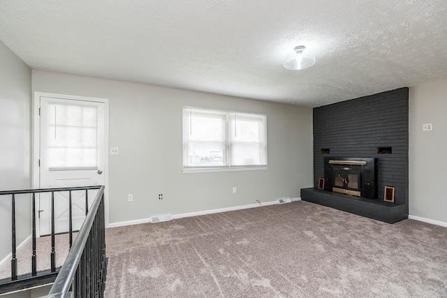 unfurnished living room featuring a textured ceiling, a fireplace, a wood stove, and carpet floors