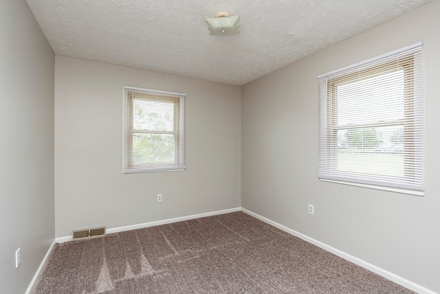 carpeted empty room featuring a textured ceiling