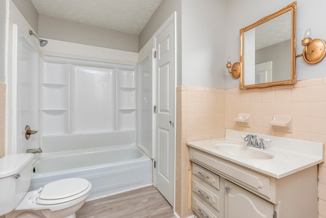 full bathroom featuring tile walls, wood-type flooring, a textured ceiling, vanity, and toilet