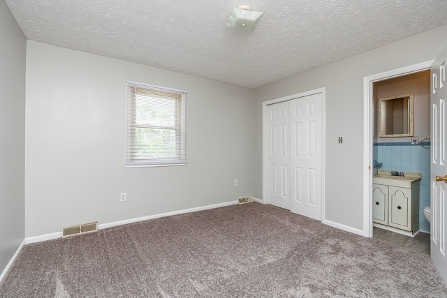 unfurnished bedroom with carpet floors, a textured ceiling, and a closet