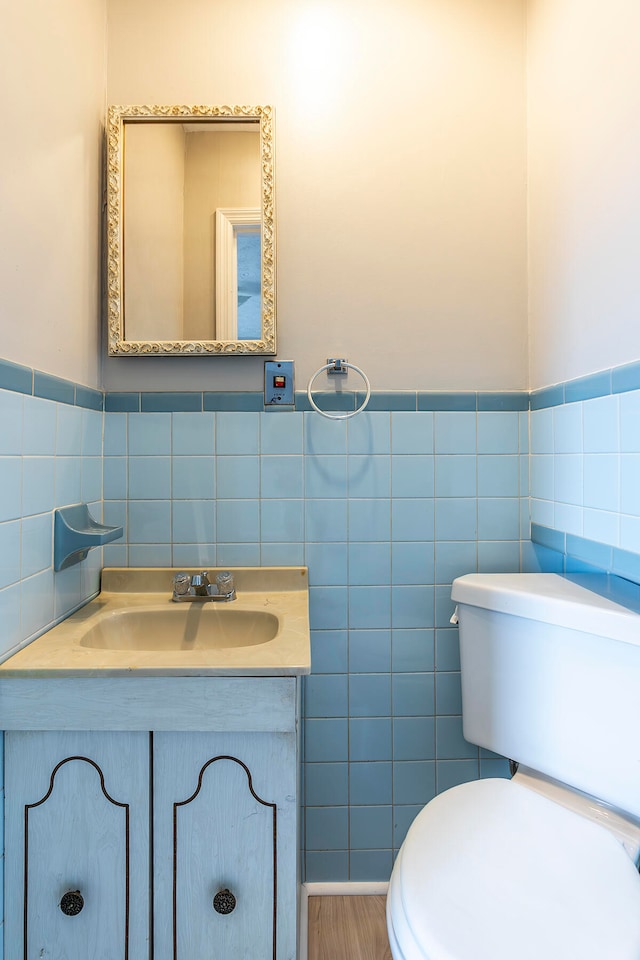 bathroom with wood-type flooring, vanity, tile walls, and toilet