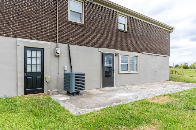 rear view of property with central AC, a patio area, and a yard