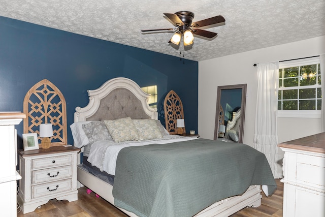 bedroom with a textured ceiling, dark wood-type flooring, and ceiling fan