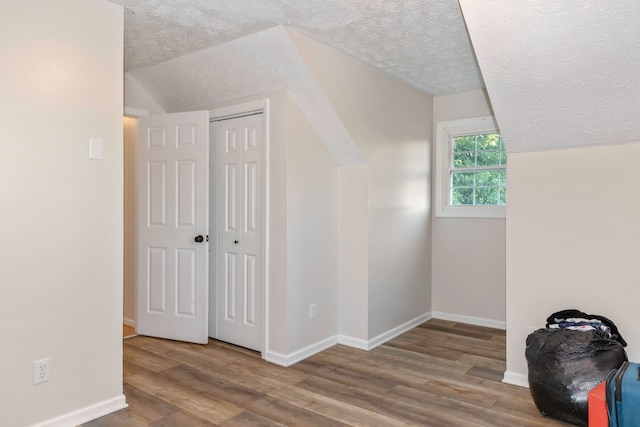 additional living space featuring a textured ceiling, wood-type flooring, and lofted ceiling