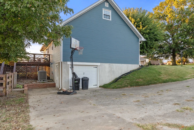 view of property exterior featuring a wooden deck, central AC, a lawn, and a garage